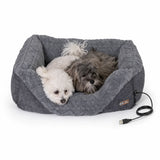 Two small dogs lying in a grey heated pet bed with USB cable, cozy and comfortable.